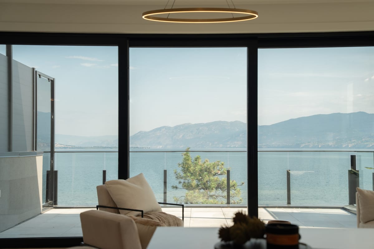 Living room with floor-to-ceiling glazing opening onto a balcony above Okanagan Lake