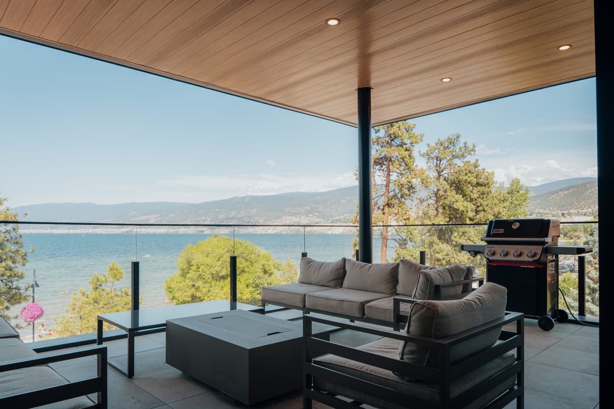 Covered patio with a cedar ceiling, lounge seating and a barbecue overlooking the lake